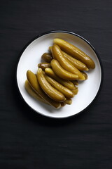 Cucumber pickles in a plate on a black background