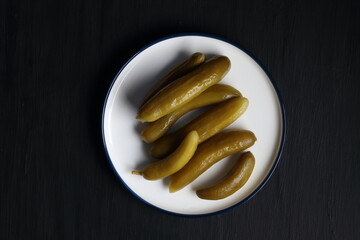 Cucumber pickles in a plate on a black background