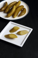 Cucumber pickles in a plate on a black background