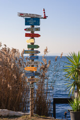 Signpost with colored tablets with the names and distances of various cities on the shores of Lake Garda