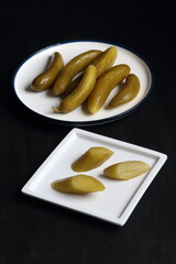 Cucumber pickles in a plate on a black background