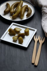Cucumber pickles in a plate on a black background