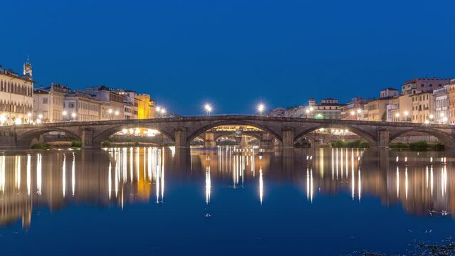 Twilight scene of Ponte Alla Carraia and Santa Trinita (Holy Trinity Bridge) day to night transition panoramic timelapse over River Arno with reflections on water after sunset. Florence, Italy