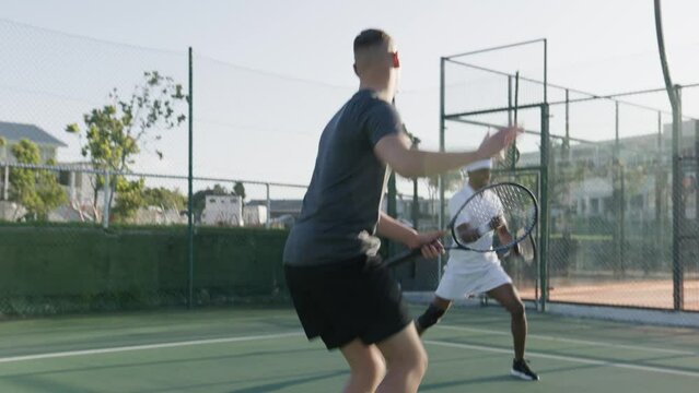 Athletic young men in sportswear play a doubles match during tennis practice at sports court