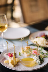 Four types of different cheeses sliced and served on a plate with honey sauce.