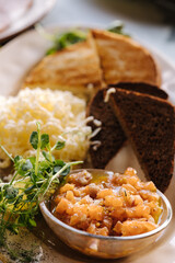 Close-up of salmon tartare served with grated butter and roasted bread. Table with food on terrace