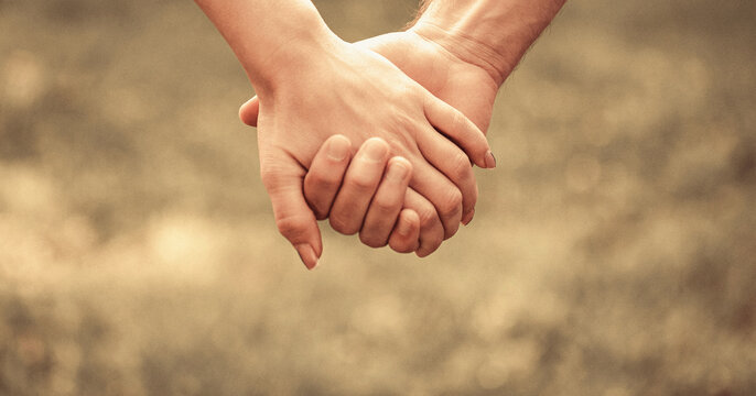 Couple hold hand in the autumn or summer park. Closeup of loving couples holding hands while walking. Female and male hand together. Couple holding hands in the Park. Hold on, hands, couples