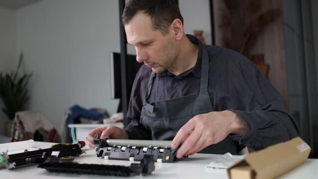 printer repair technician. A male handyman repairs a printer in a client's apartment. Fuser part