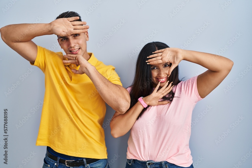 Poster young couple standing over isolated background smiling cheerful playing peek a boo with hands showin