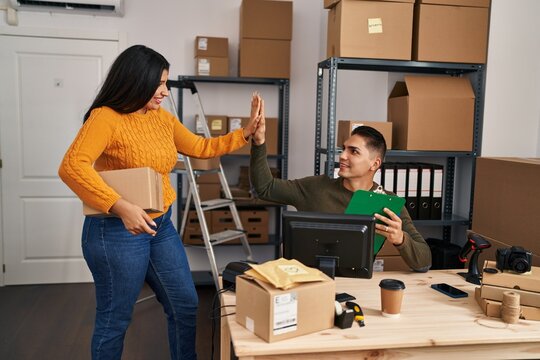 Man and woman ecommerce business workers high five with hands raised up at ecommerce office