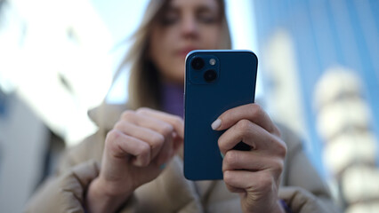 Young blonde woman using smartphone at street