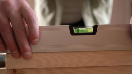 a male craftsman measures the plane with the building level of his working project. close-up.