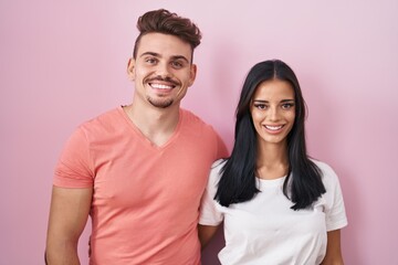 Fototapeta premium Young hispanic couple standing over pink background with a happy and cool smile on face. lucky person.