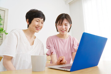 家でパソコンを使う母親と娘