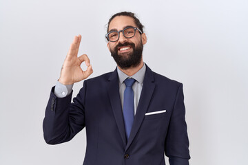 Hispanic man with beard wearing suit and tie smiling positive doing ok sign with hand and fingers. successful expression.