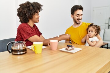 Fototapeta premium Couple and daughter having breakfast sitting on table at home
