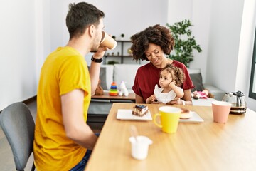 Couple and daughter having breakfast sitting on table at home