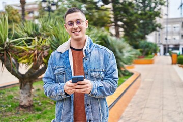 Obraz premium Young hispanic man smiling confident using smartphone at park