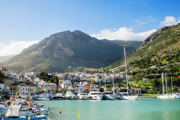 Fototapeta na wymiar View of Castellammare del Golfo town, Sicily island, Italy. Beautiful mediterranean port with fishing boats and yachts over old town and mountain background. Popular travel destination in Europe
