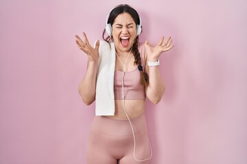 Young brunette woman wearing sportswear and headphones celebrating mad and crazy for success with...