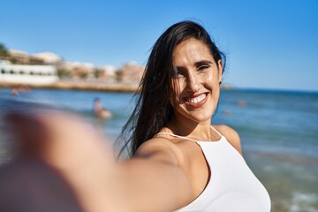 Young hispanic woman smiling confident making selfie by the camera at seaside