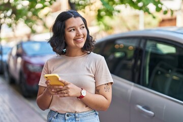 Fototapeta premium Young woman smiling confident using smartphone at street