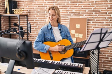 Young blonde woman musician singing song playing spanish guitar at music studio