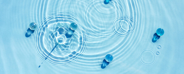Texture of blue water with circles, ripples and transparent granules.
