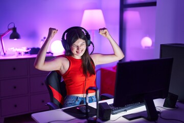 Fototapeta na wymiar Young caucasian woman streamer playing video game with winner expression at gaming room