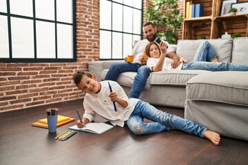 Family watching tv and son drawing on notebook at home