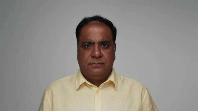 Portrait of Adult Indian Man Looking at Camera in Color Studio Shot. Old Male of India Isolated Alone on Grey Background Closeup. Ethnic Aged Person Opening Focused Eyes with Normal or Serious Face
