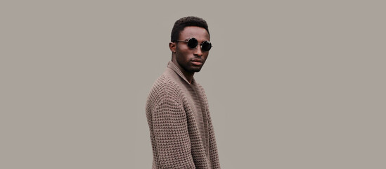 Portrait of stylish young african man model wearing knitted cardigan isolated on gray background - obrazy, fototapety, plakaty
