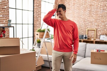 Hispanic man moving to a new home surprised with hand on head for mistake, remember error. forgot,...