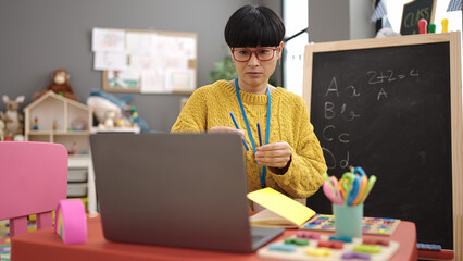 Young chinese woman preschool teacher having online class at kindergarten