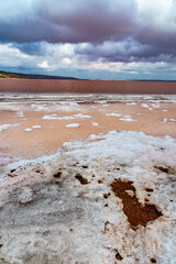 The bottom of the dried-up Kuyalnitsky estuary, covered with a layer of white self-precipitating table salt, clouds are reflected in the water
