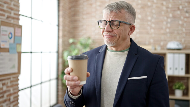 Middle age grey-haired man business worker smiling confident drinking coffee at office