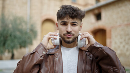 Young arab man standing with serious expression at street
