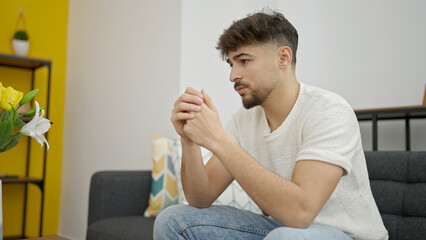 Young arab man sitting on sofa with relaxed expression at home