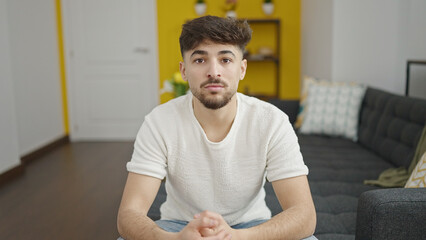 Young arab man sitting on sofa with relaxed expression at home