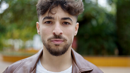 Young arab man standing with serious expression at park