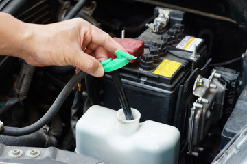 Obraz premium Closeup hand hold bottle tank of car engine coolant. Concept, automobile maintenance. Check and repair before driving for safety. Basic diagnose vehicle problems. 