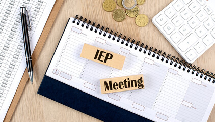 IEP MWWTING word written on wooden block on planner with coins, clipboard and a calculator