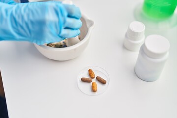 Fototapeta na wymiar Middle age woman scientist mixing pills on bowl at laboratory