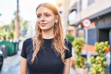 Young blonde woman smiling confident looking to the side at street