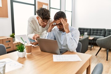 Two hispanic men business workers arguing at office