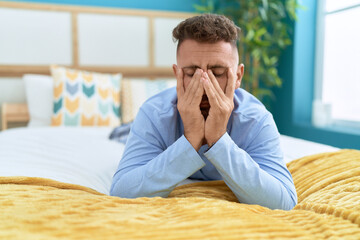 Young hispanic man stressed lying on bed at bedroom