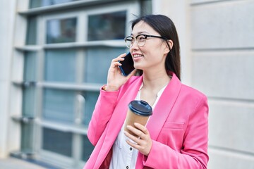 Chinese woman business worker talking on smartphone drinking coffee at street