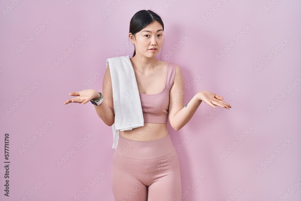 Poster Chinese young woman wearing sportswear and towel clueless and confused with open arms, no idea concept.