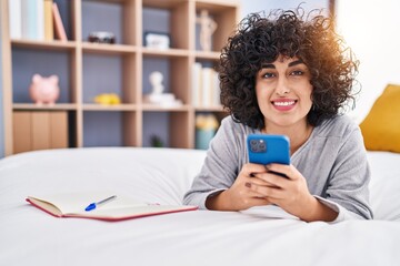 Young middle east woman using smartphone lying on bed at bedroom