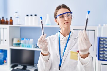 Young caucasian woman scientist holding test tubes at laboratory